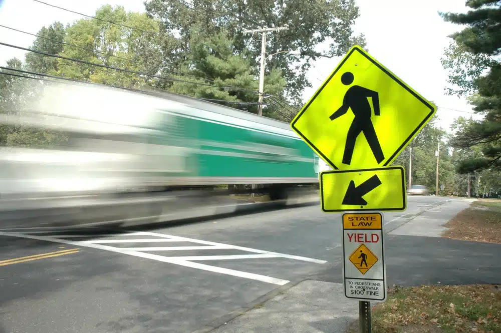 Cars driving over crosswalk with yield sign in focus