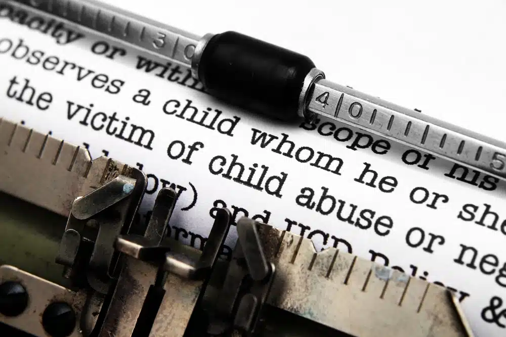 Close up text on paper in a type writer focused on the words victim of child abuse